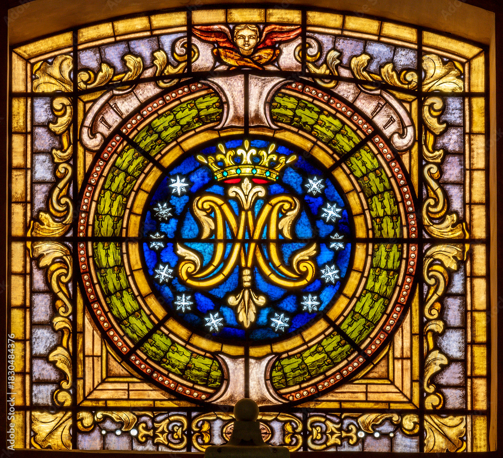Fototapeta premium SALERNO, ITALY - OCTOBER 6, 2025: The the stained glass with the marianic initials in the church Chiesa della Santissima Annunziata by unknown artist.