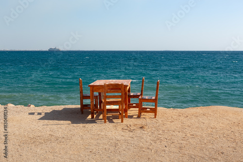Fototapeta Naklejka Na Ścianę i Meble -  Wooden table and chairs on a beach by the Mediterranean Sea.