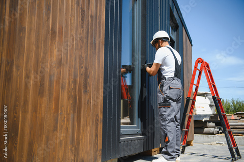 Construction worker installing window on modular house