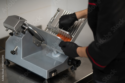 Foto Chef using electric slicer to cut sausage in restaurant kitchen