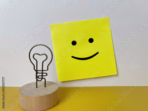 Positive mindset concept with a smiley face sticky note and a light bulb idea symbol.