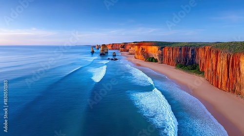 Aerial view of the Twelve Apostles rock formations along the coastline of Australia, with waves crashing on the beach at sunset.
