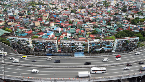 High angle drone view of the San Andres and Paco districts in Manila, Philippines. A busy elevated expressway with cars and buses curves across the foreground.