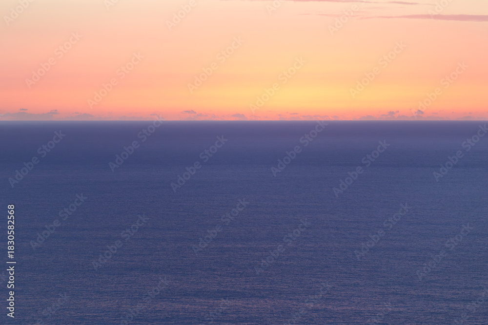 Obraz premium Sea horizon at sunset, with warm color gradients in the sky and calm water. Minimalist and soothing seascape.