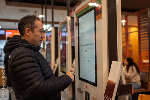 Man using self-service kiosk for ordering food at restaurant