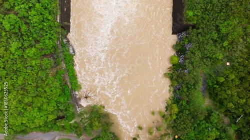 Aerial Tilt Up from Rushing Spillway Floodwaters to La Boca Dam and Santiago Cityscape