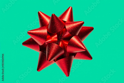 Vibrant red metallic gift bow against a bright teal background