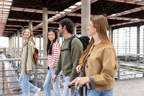 Group of young friends on the way to the train station, smiling and talking