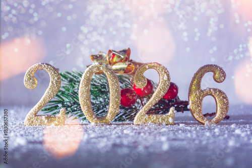 Festive 2026 New Year numbers in sparkling gold glitter with pine branch on white snow background. Concept holiday greeting card design for celebrating upcoming year with winter Christmas decorations.