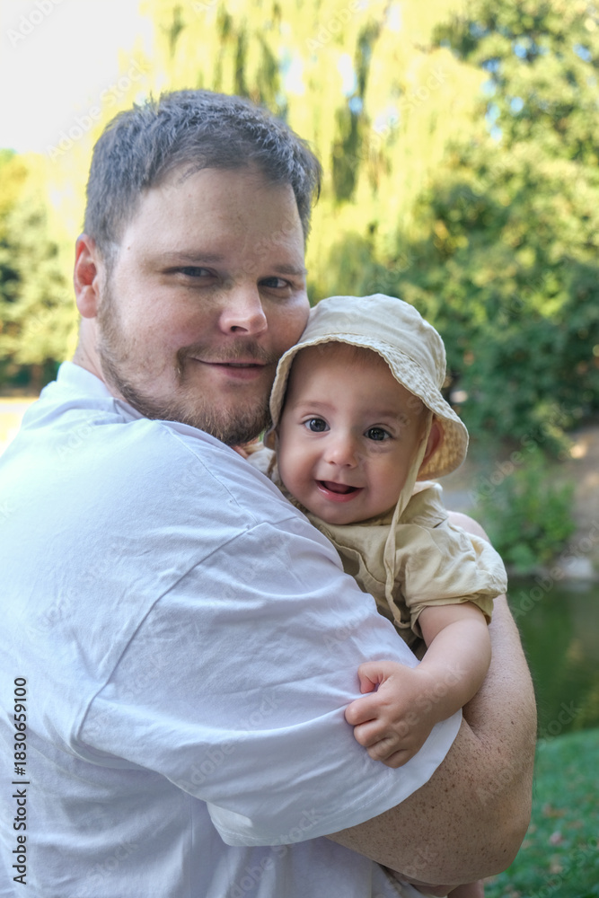 Fototapeta premium Father Holding Smiling Baby in Park Portrait