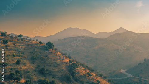 Hazy valley with hills and olive trees during sunset. Almogia, Malaga, Andalucia, Spain.