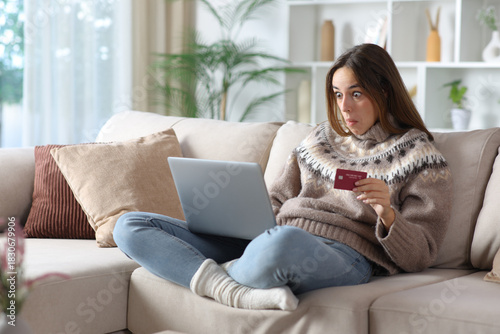 Perplexed woman in winter buying online at home
