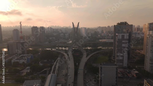 aerial view of a cable stayed bridge in Sao Paulo city during sunset with skyscrapers, traffic and a river