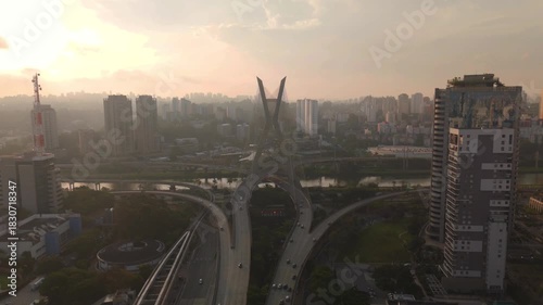 aerial view of a cable stayed bridge in Sao Paulo city during sunset with skyscrapers, traffic and a river