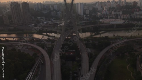 aerial view of a cable stayed bridge in Sao Paulo city during sunset with skyscrapers, traffic and a river