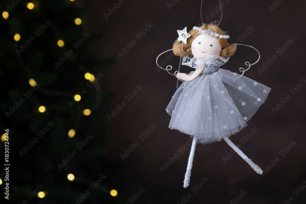 Obraz premium Christmas decor. Fairy doll hanging on black background with blurred lights, closeup. Space for text