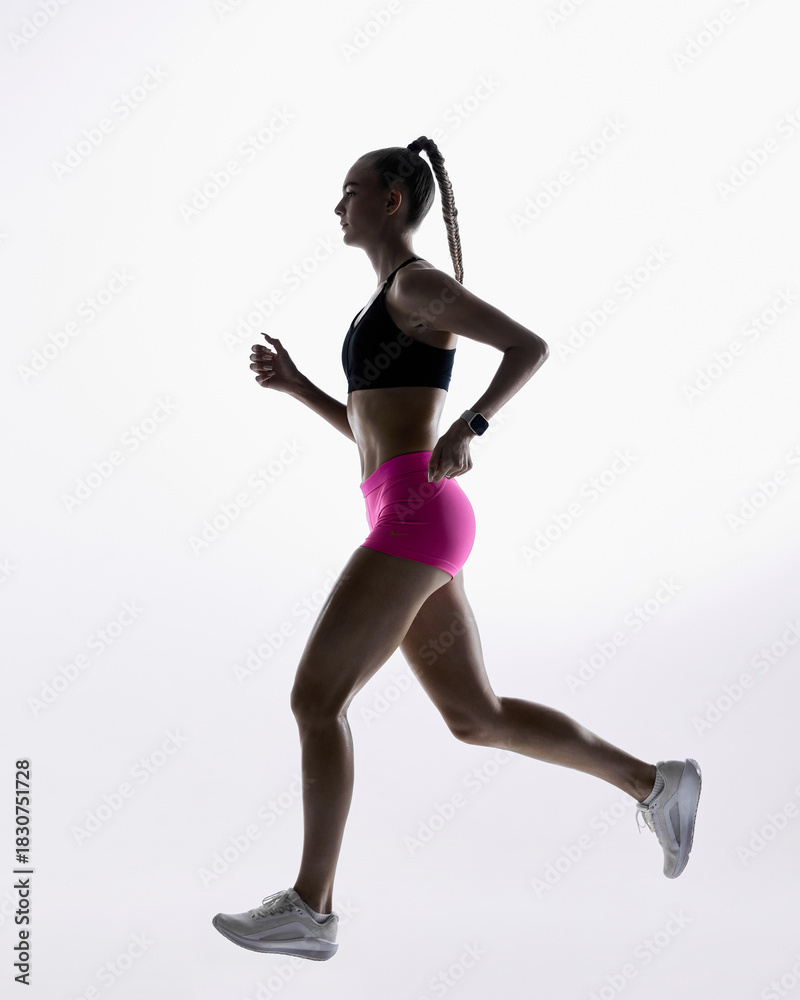 Fototapeta premium Female athlete jogging in clean minimal studio light. Concept of cardio demonstration, exercise tutorials, sports program visuals, movement analysis, and fitness education materials.