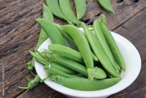 Fresh green peas in wooden bowl close-up