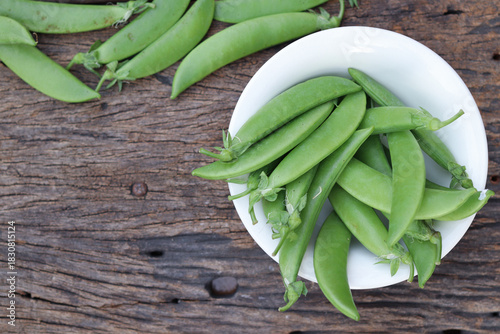 Fresh green peas in wooden bowl close-up