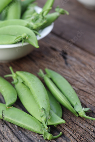 Fresh green peas in wooden bowl close-up