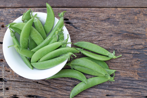 Fresh green peas in wooden bowl close-up