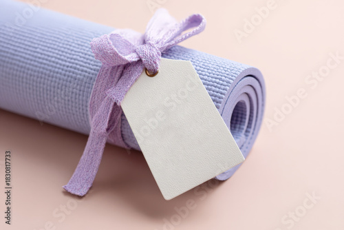 Purple yoga mat with blank tag and bow on pastel background