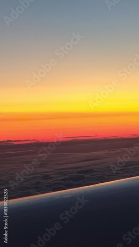 flying above clouds with orange sunset dusk sunrise gradient sky plane wing view vertical footage