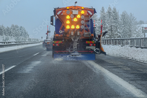 Winter service truck spreading salt on a snow covered highway during a cold day