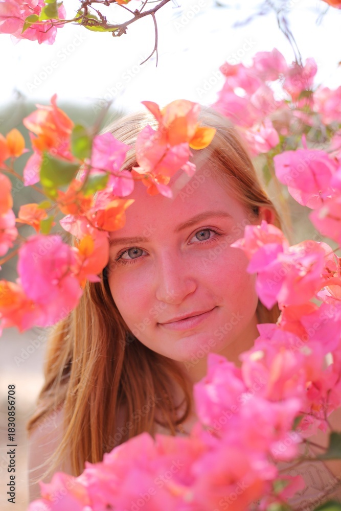 Fototapeta premium Woman gently smelling bright bougainvillea flowers outdoors on a sunny day, enjoying a calm and natural moment.