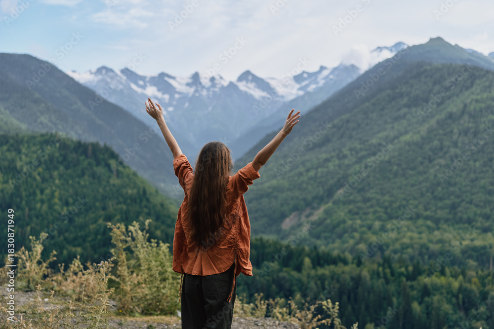 Obraz premium Woman in mountains raising arms for freedom and nature, authenticity inclusivity