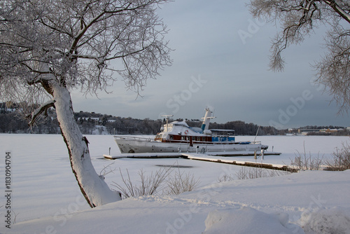 An old boat moored on a frozen lake on a winter day