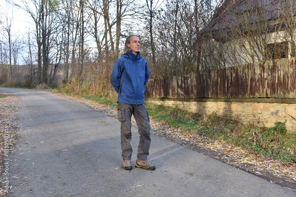 Obraz premium Man standing on an autumn road in blue jacket