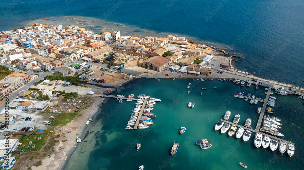 Fototapeta premium Aerial view of the marina of the town of Marzamemi, in the province of Syracuse, Sicily, Italy. It is a coastal village overlooking the crystalline waters of the Mediterranean Sea. Sunny summer day.