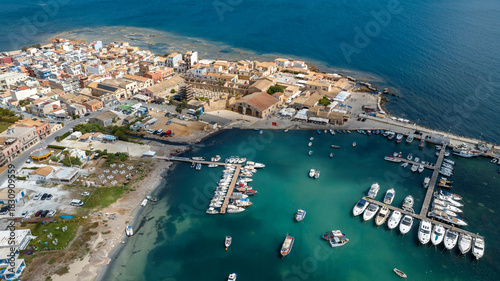 Aerial view of the marina of the town of Marzamemi, in the province of Syracuse, Sicily, Italy. It is a coastal village overlooking the crystalline waters of the Mediterranean Sea. Sunny summer day.