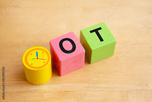 Overtime working concept; Clock on wooden block and letter OT