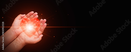 Hands gently holding a glowing red heart against a dark background, Health care, CSR, insurance, family, World Heart Day, World Health Day, love, rescue, wellbeing, hope, support, and compassion