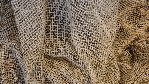 close up of a tangled weathered old fishing net (rope net) , weathered beige ropes forming a repetitive diamond grid pattern with copy space