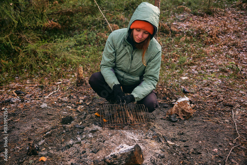A young woman holds a barbecue grill in her hands. Picnic in the autumn forest, grilling meat in a campsite