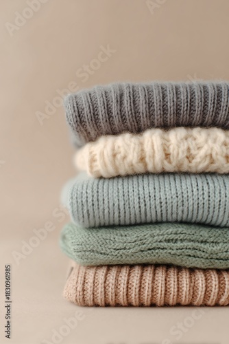 Stack of chunky knitted sweaters folded neatly, mixed rib and cable textures
