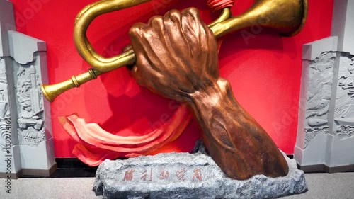 Bronze Hand Holding Golden Trumpet Victory Sculpture with Red Background and Relief Art Panels