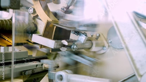 A close-up view of intricate machinery precisely wrapping chocolate candies in colorful paper packaging during factory production.