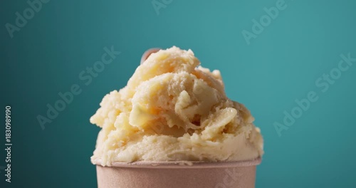 yellow mango and pineapple sorbet in paper cup turning on colorful background, food closeup