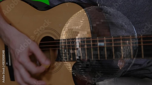 Right hand poised, plucking and strumming guitar strings, mirrored disc shifting, showing technique