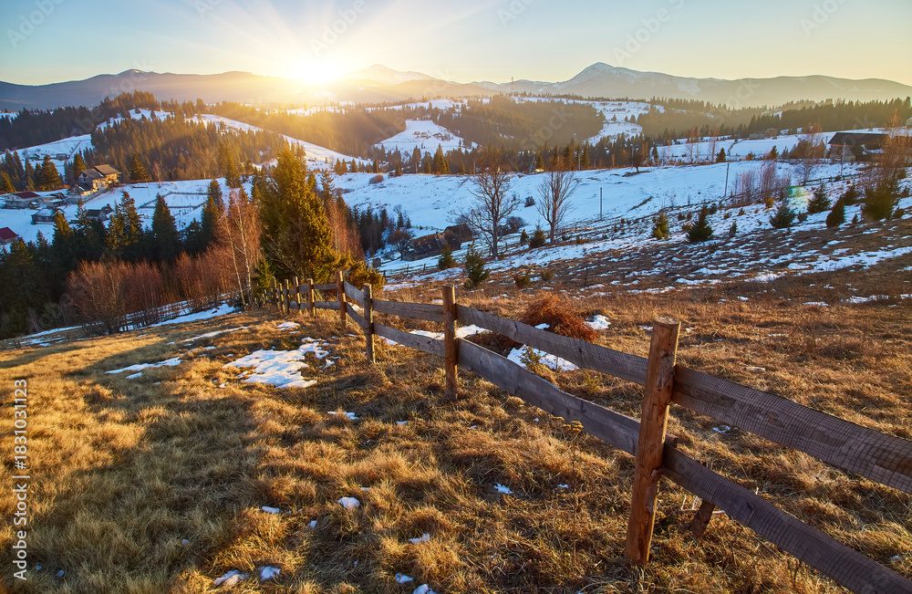 Fototapeta premium Rustic wooden fence on a mountain meadow with snowy peaks in the background.