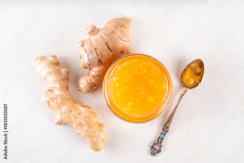 Fototapeta premium Homemade caramelized ginger jam marmalade preserves in small jar with fresh ginger roots on white table copy space