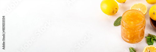 Sweet and sour lemon citrus jam marmalade preserves in small jar with fresh ginger, lemons and mint, on white table copy space