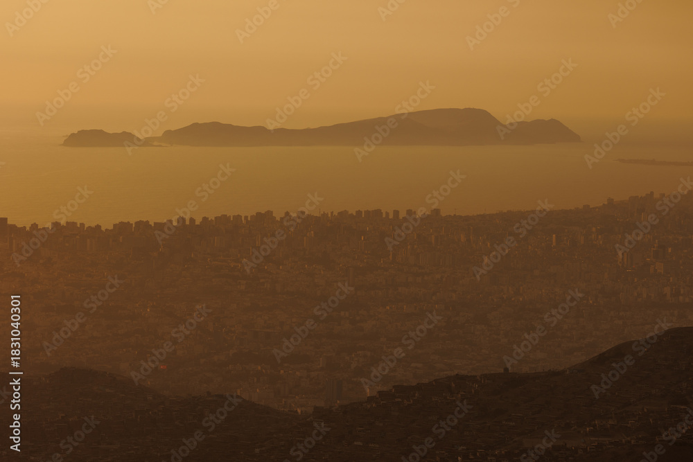 Obraz premium Hillside shantytown contrasting with a distant modern city skyline in the mist, illustrating social inequality, poverty, and urban sprawl in Lima, Peru