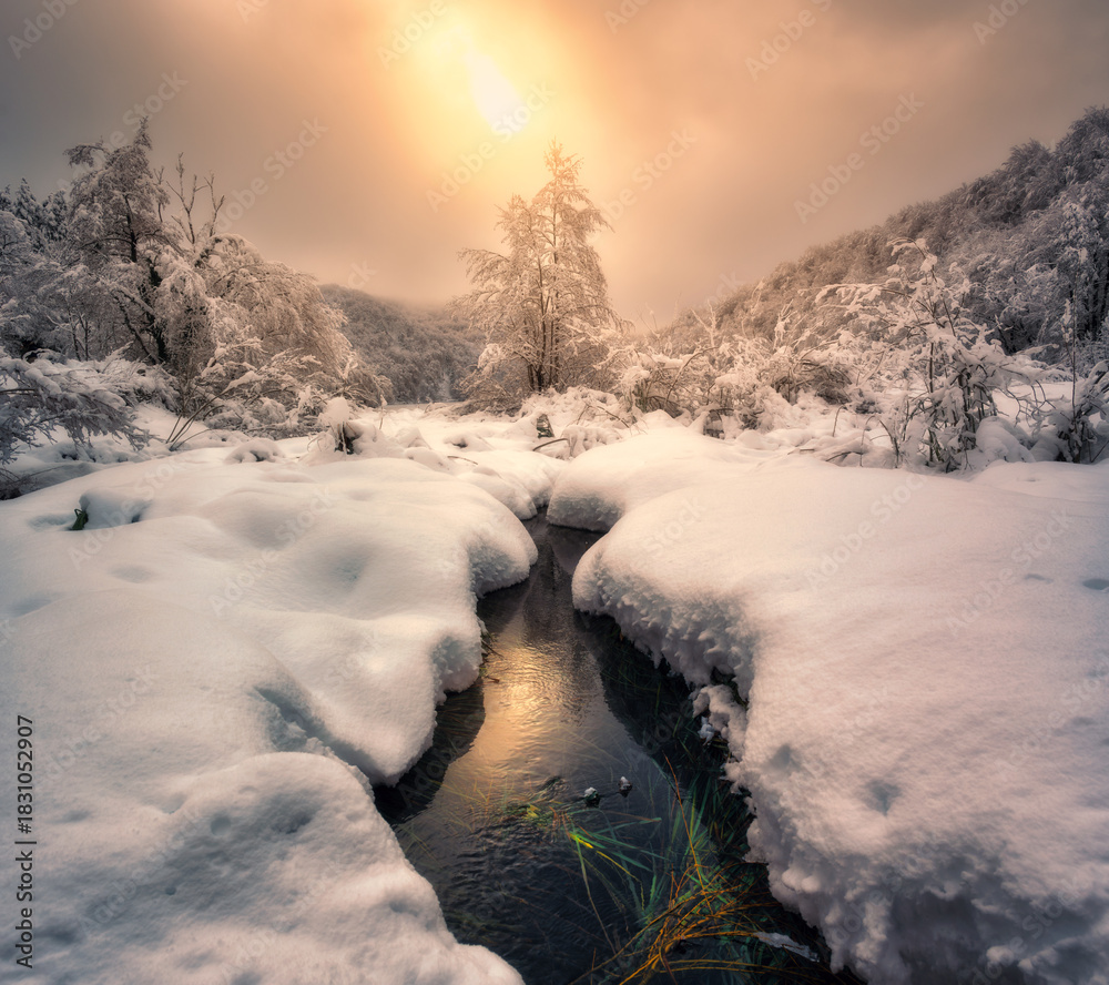 Fototapeta premium Scenic view of frozen ice lake surrounded by snow-covered trees at sunrise. Landscape with lake, hills with snowy trees. Magical winter wonderland at dawn. Winter fairytale in Plitvice Lakes, Croatia