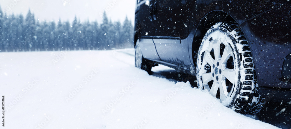 Naklejka premium Car on snowy country road, closeup. Adverse weather conditions