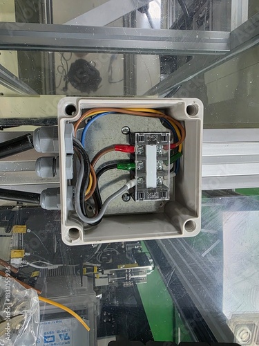 Electrical junction box with multiple colored wires connected to terminals, showcasing intricate wiring and components in a modern industrial setting